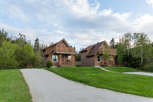 Two wooden cabins with a gravel path leading to a picnic table.