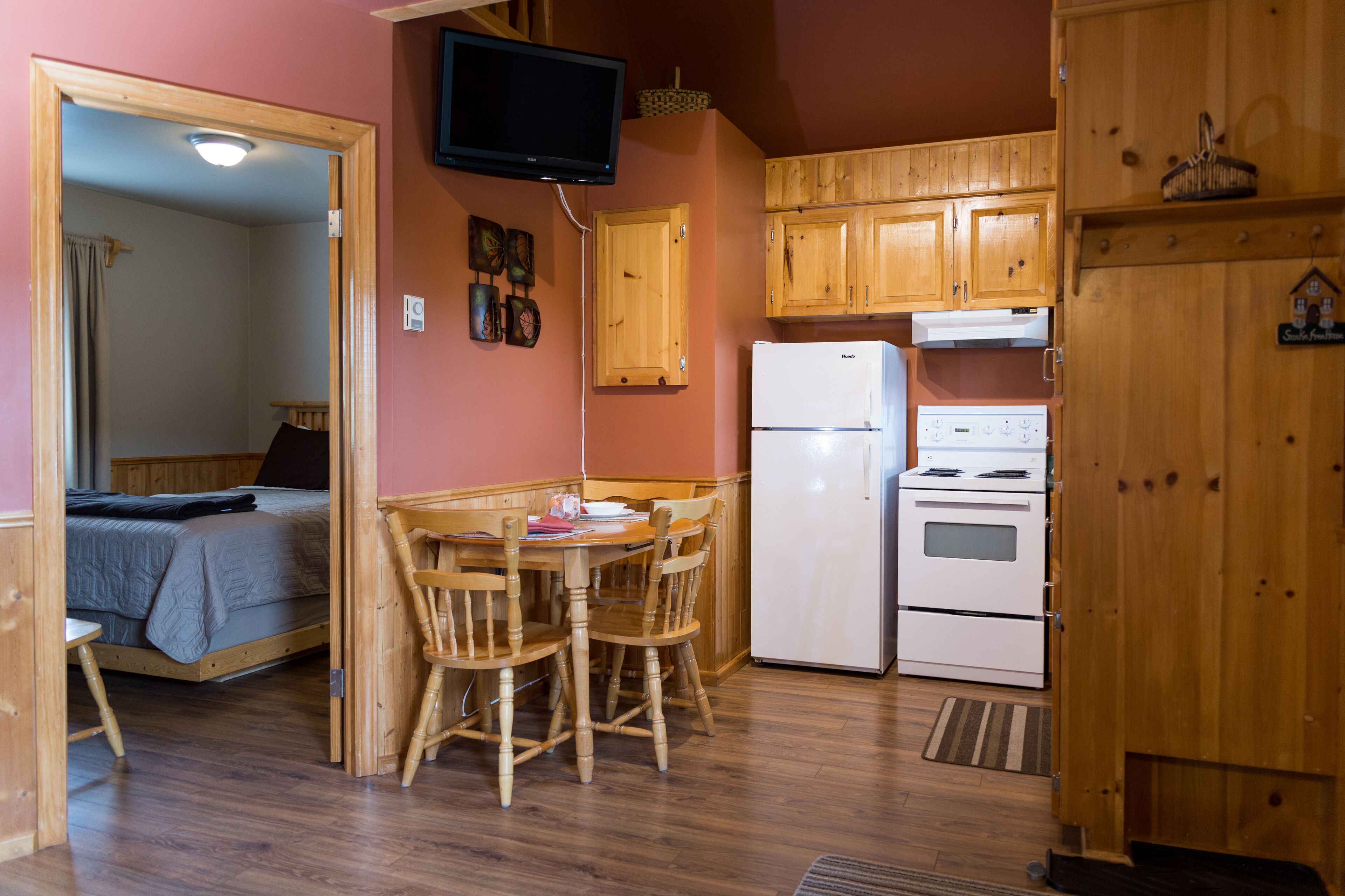 Una cocina compacta con armarios de madera, un refrigerador y un comedor con una mesa y sillas.