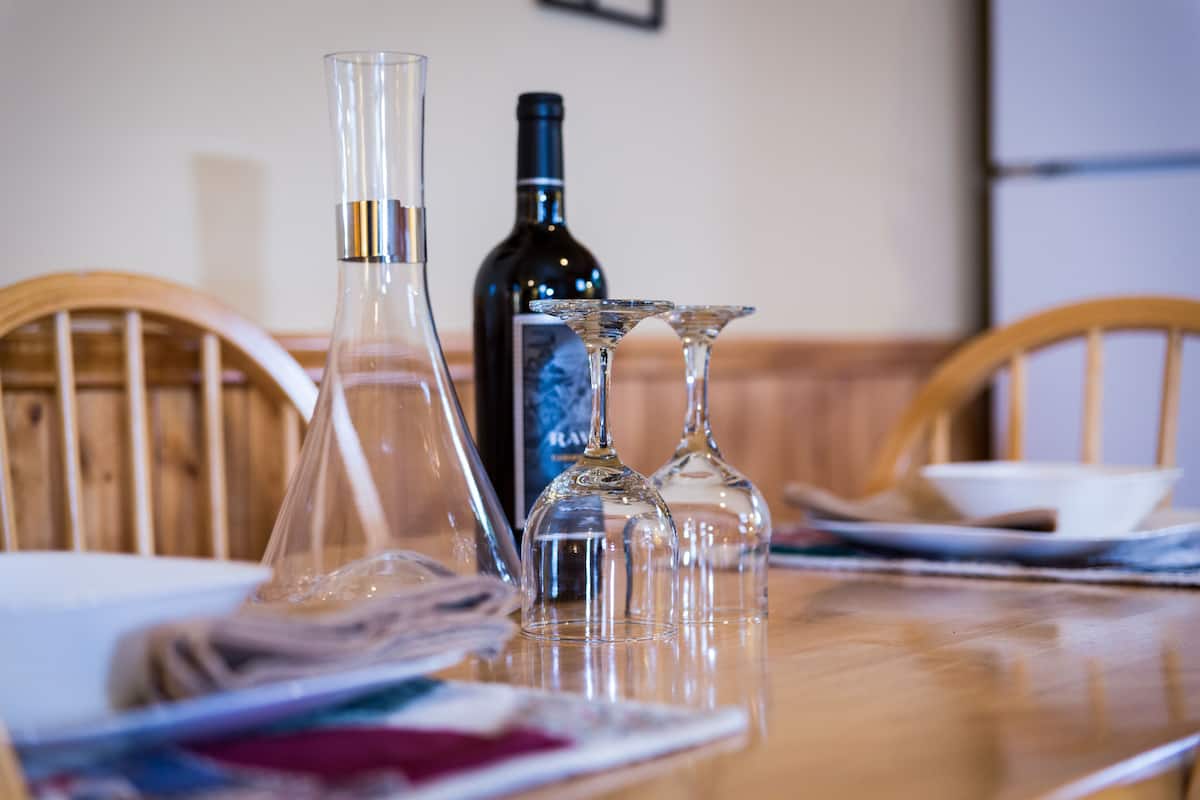A dining table with a wine bottle, two wine glasses, and a clear glass decanter.