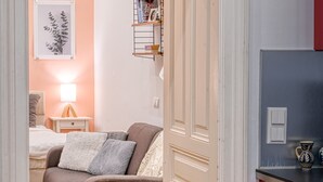Ett mysigt vardagsrum med en soffa, ett sidobord med en lampa och en bokhylla.