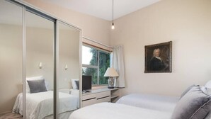 A bedroom with a bed, a desk, a chair, a lamp, a painting, and a window. - Oceanbeach Escape - Mount Maunganui (Mount Maunganui)