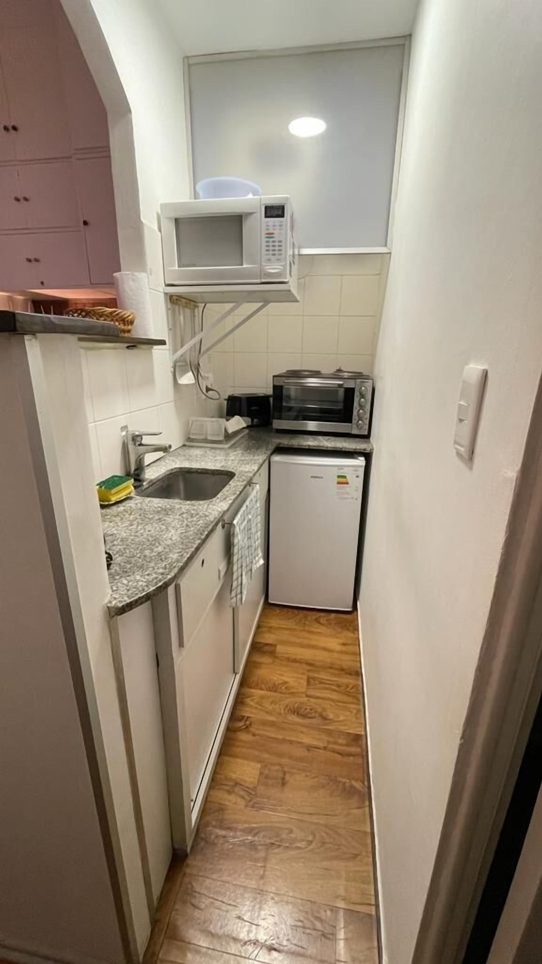 A narrow kitchen with a microwave, toaster, and small refrigerator.