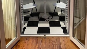 Una habitación con piso a cuadros, una mesa pequeña con dos sillas y vista al océano.