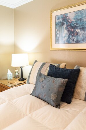 Relax in a serene space with a large bed, bedside table, and elegant artwork.