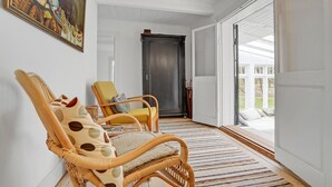 Una habitación con sillas de mimbre, una puerta de madera y vistas al exterior.