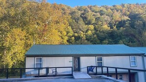 A single-story building with a green roof, a front entrance, and a small parking area with a few chairs. - Large group & couples retreat (Pineville)
