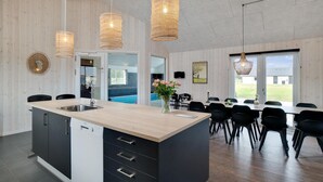 A modern kitchen with a central island, black cabinets, and a built-in dishwasher. There are three pendant lights hanging above the island. - Nice home in Nørre Nebel with sauna (Nørre Nebel)