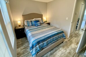 A bedroom with a large bed, two bedside tables, and a nightstand. - Rainbow River Bungalow T (Dunnellon)