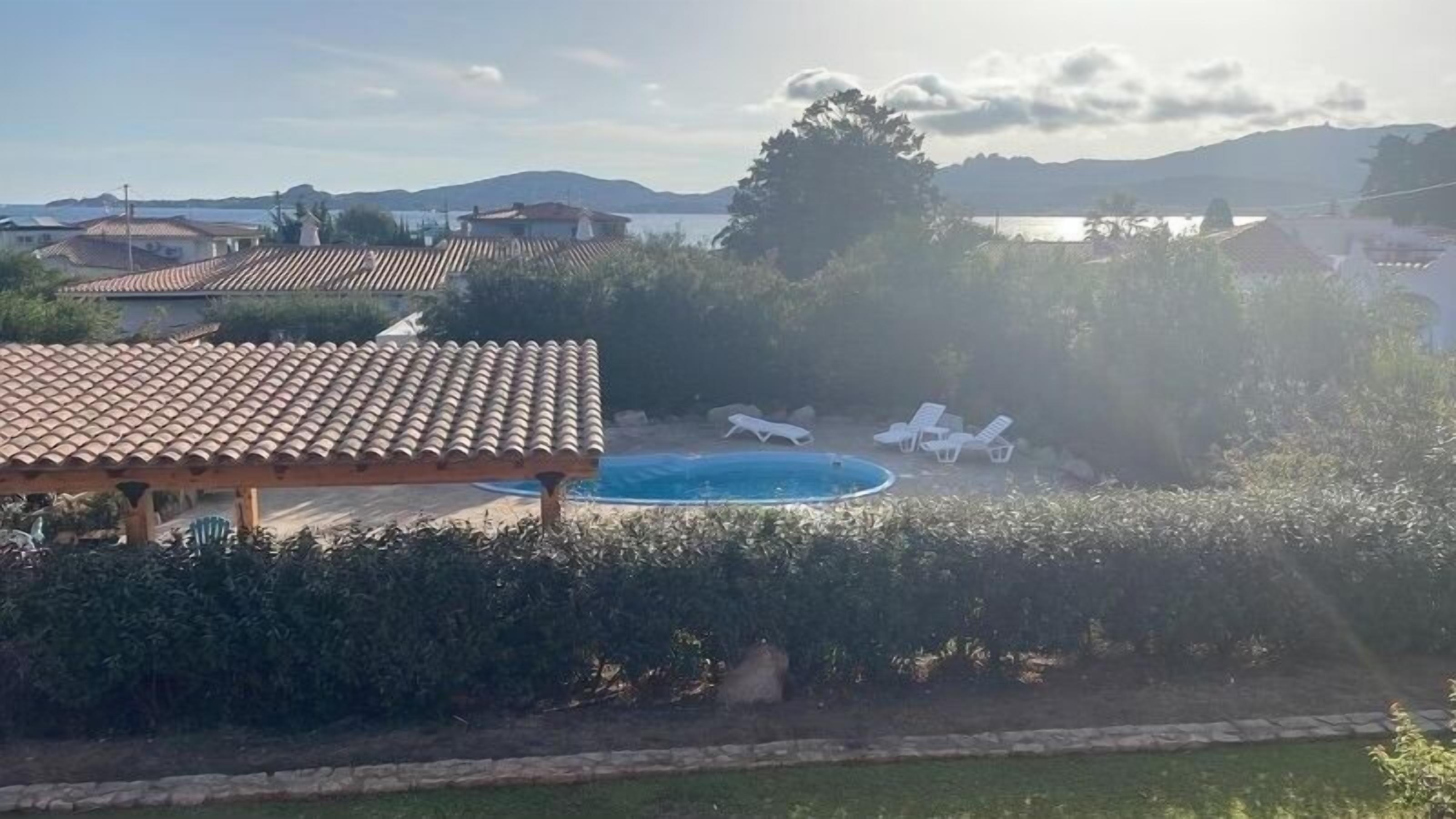 Ein Wohngebiet mit Schwimmbad, Liegestühlen und einer Pergola.