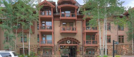 A multi-story hotel with a stone facade, multiple balconies, and a central entrance with a decorative arch.
