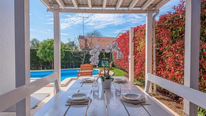 A covered outdoor dining area with a view of a swimming pool and a garden. - Luxurious home in Vodice (Vodice)