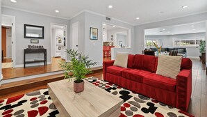 Una sala de estar moderna con un sofá rojo, una mesa de centro de madera y una alfombra estampada.