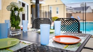 Una mesa dispuesta para comer, con un florero, una vela azul y un plato.