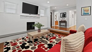 Una sala de estar moderna con televisor de pantalla plana, chimenea, mesa de centro y sofá rojo.