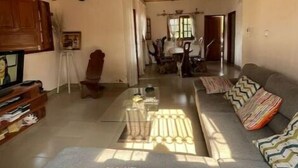 Un salon spacieux avec un plafond haut, un ensemble de canapés, un coin repas et un téléviseur.