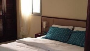Una camera da letto con un letto, una finestra, un condizionatore d'aria e un comodino.