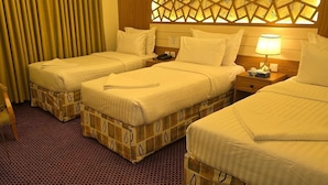 A hotel room with two single beds, a small round table, a chair, and a decorative wall panel. - Hotel  Karam Al Madina (Madinah)