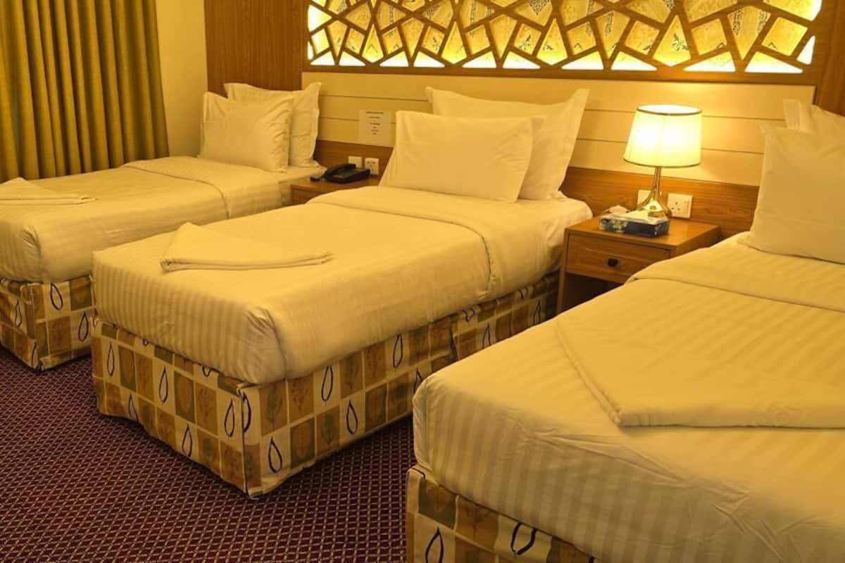 Une chambre d’hôtel avec deux lits simples, une petite table ronde, une chaise et un panneau décoratif mural.