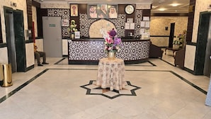A hotel lobby with a reception desk, a clock, and a decorative star pattern on the floor. - Hotel  Karam Al Madina (Madinah)