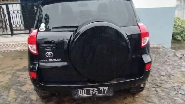 Een zwarte Toyota RAV4 staat op een stenen oprit.