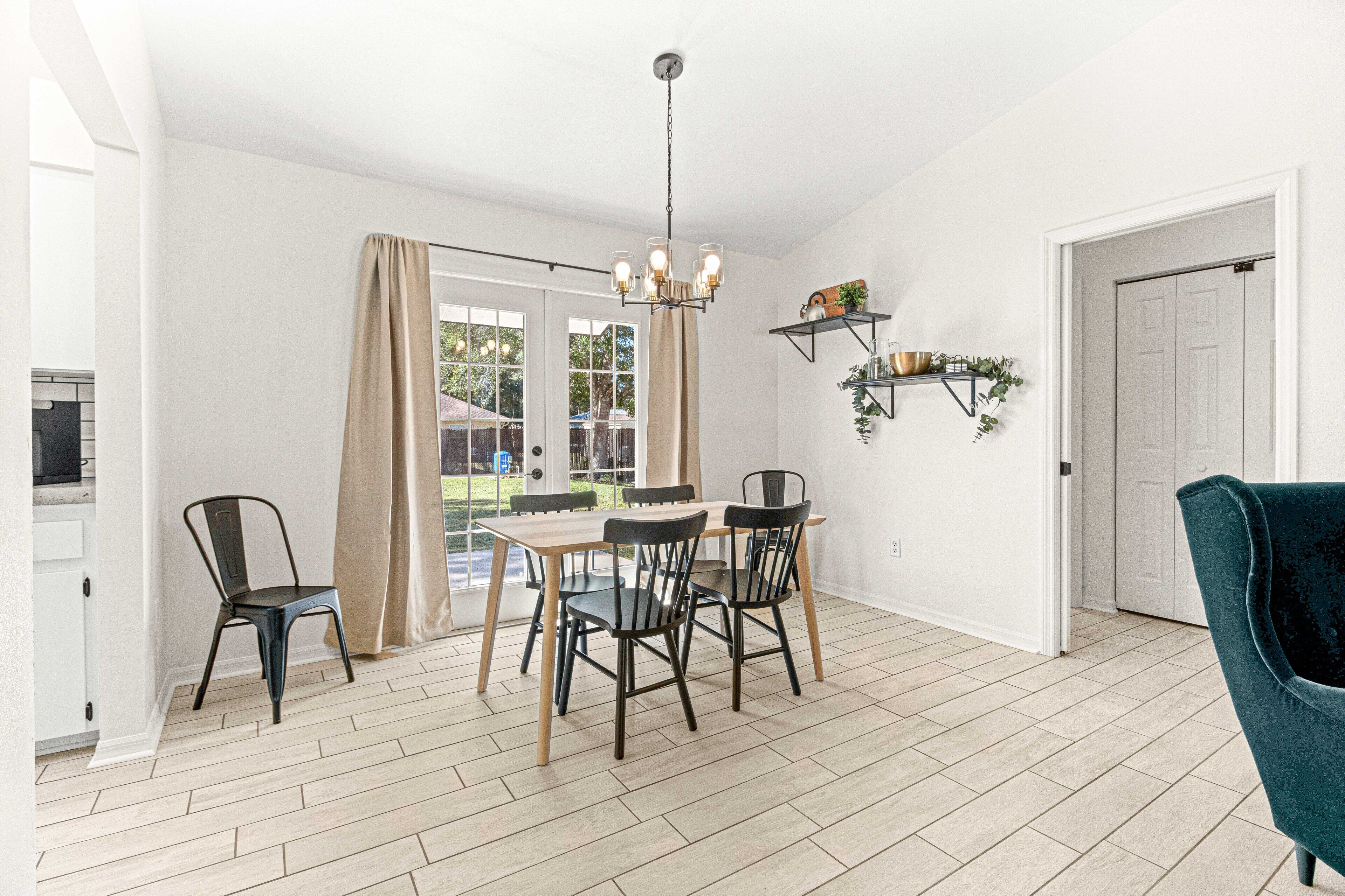 Un coin repas avec une table et des chaises, un lustre et une vue par la fenêtre.