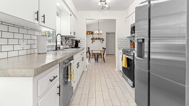 A modern kitchen with white cabinets, a stainless steel refrigerator, and a tiled backsplash. - Greenway Getaway Near Silver Springs, walking distance to Cross Florida Greenway (Ocala)