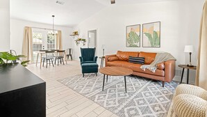 A spacious living room with a leather sofa, a coffee table, and a dining area with chairs and a table. - Greenway Getaway Near Silver Springs, walking distance to Cross Florida Greenway (Ocala)