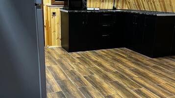 Una cocina con pared de madera, armarios negros y un refrigerador de acero inoxidable.