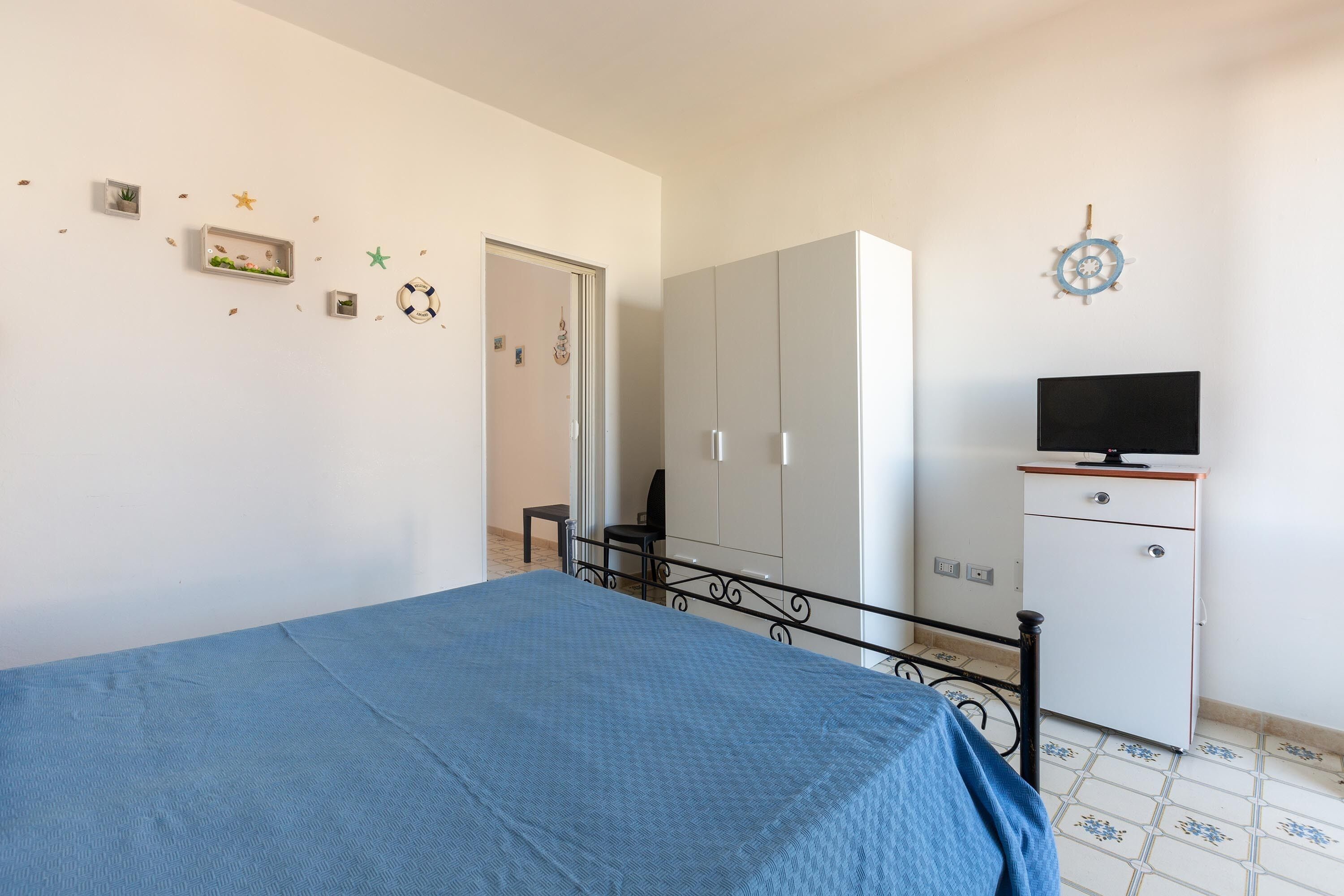 Un dormitorio con cama, armario, televisor y pegatinas decorativas en la pared.