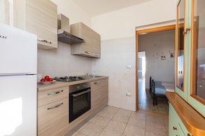 A modern kitchen with a white refrigerator, a stove, and wooden cabinets. - 2699 Sud Sud Apartaments - Appartamento Corallo by Barbarhouse (Porto Cesareo)
