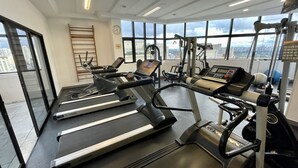 A gym with treadmills, exercise bikes, and weight machines. - Três de Julho Flats - Jardins II (São Paulo)