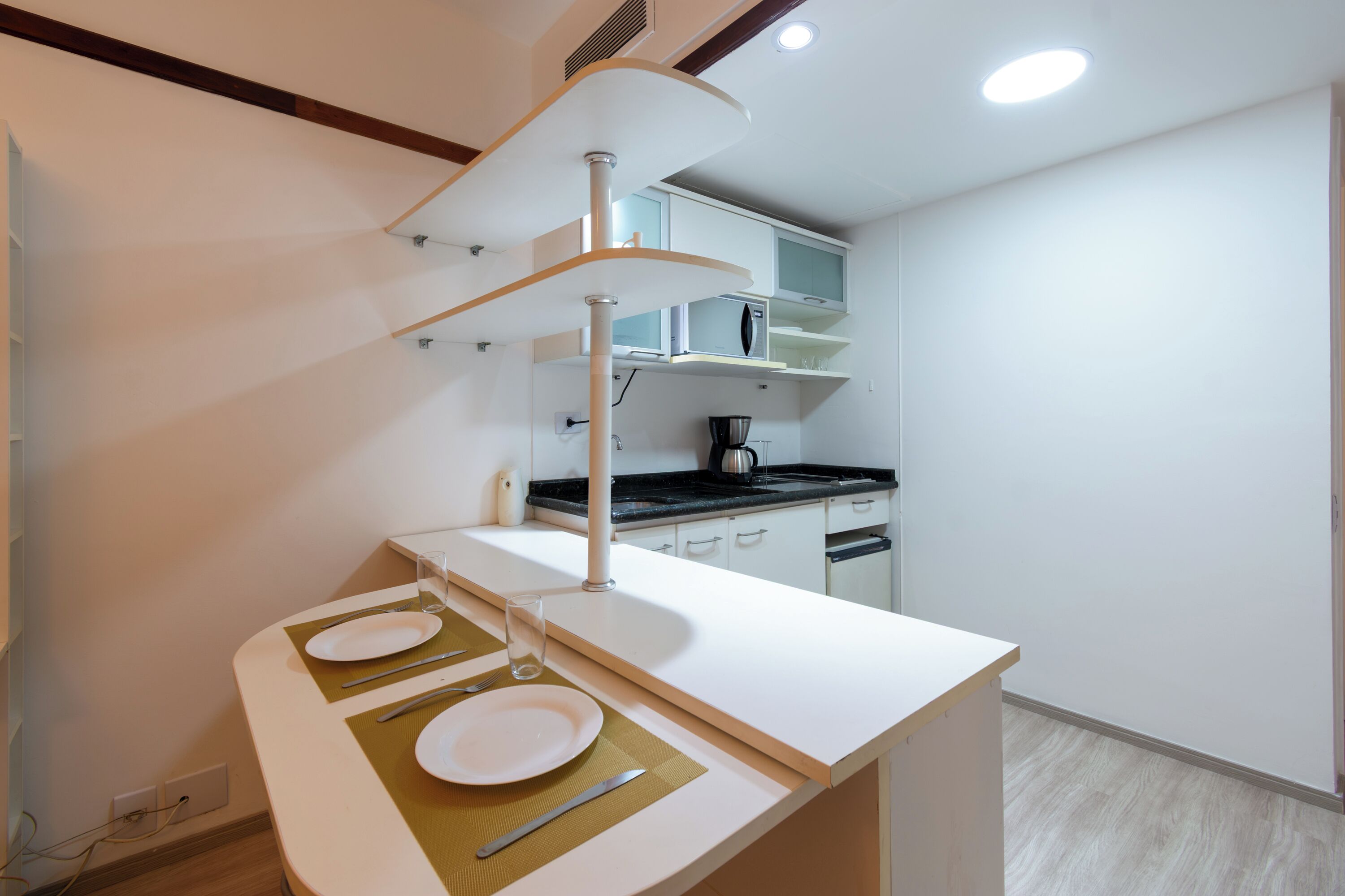 A modern kitchen with white cabinetry, a built-in microwave, and a coffee maker.