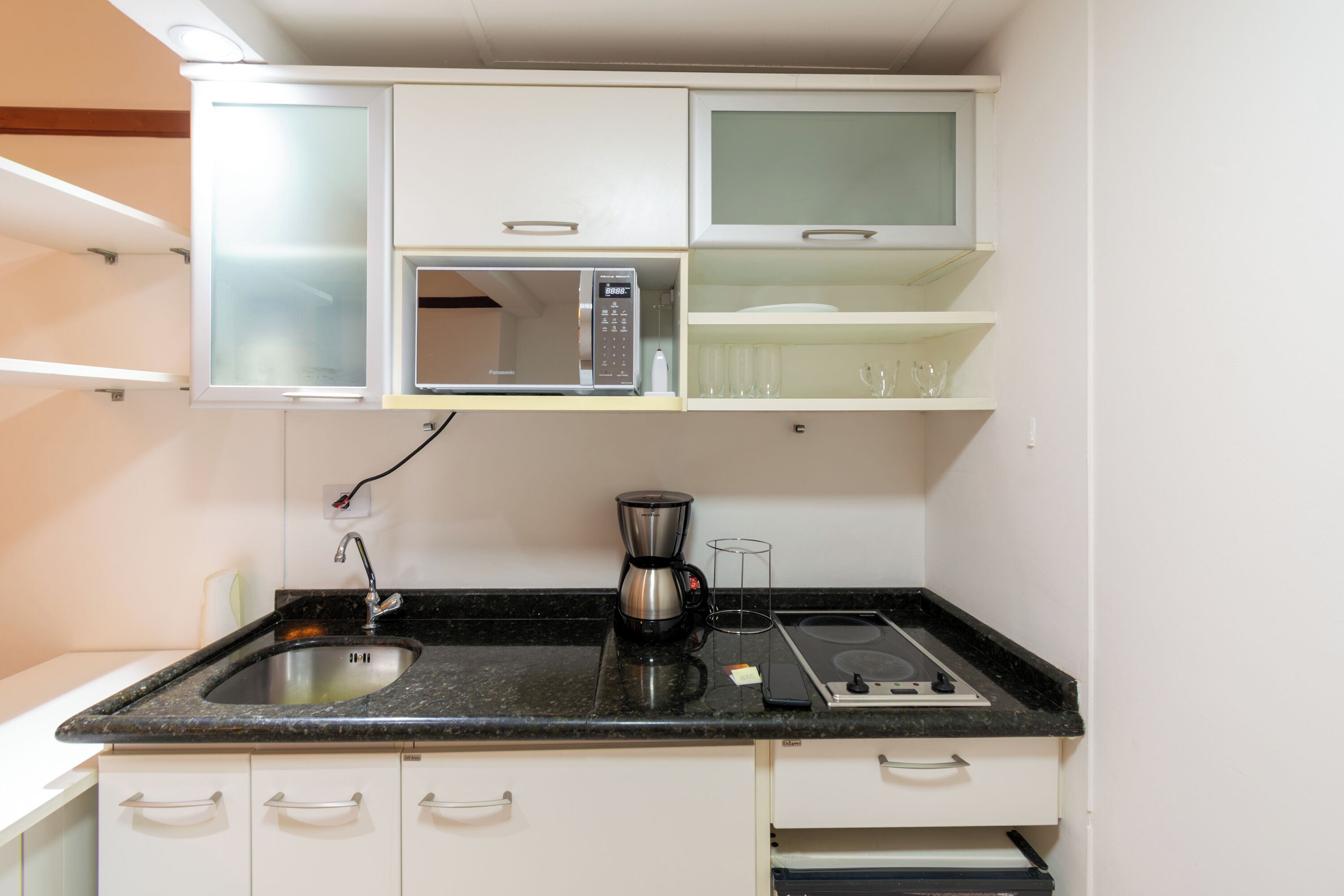 A kitchen with a microwave, coffee maker, and a sink.