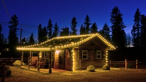 Un rustico chalet con veranda decorata da luci a stringa, immerso tra gli alberi.
