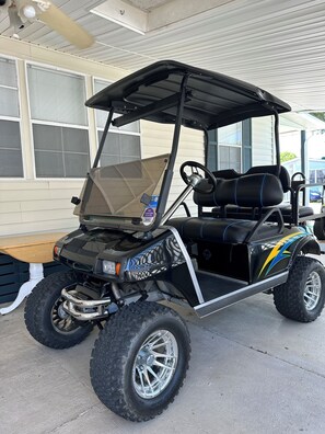 A golf cart with a black and yellow design, large tires, and a canopy.
