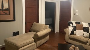 Een woonkamer met twee beige banken, een bijzettafeltje met decoratieve objecten en een lijst met een afbeelding aan de muur.