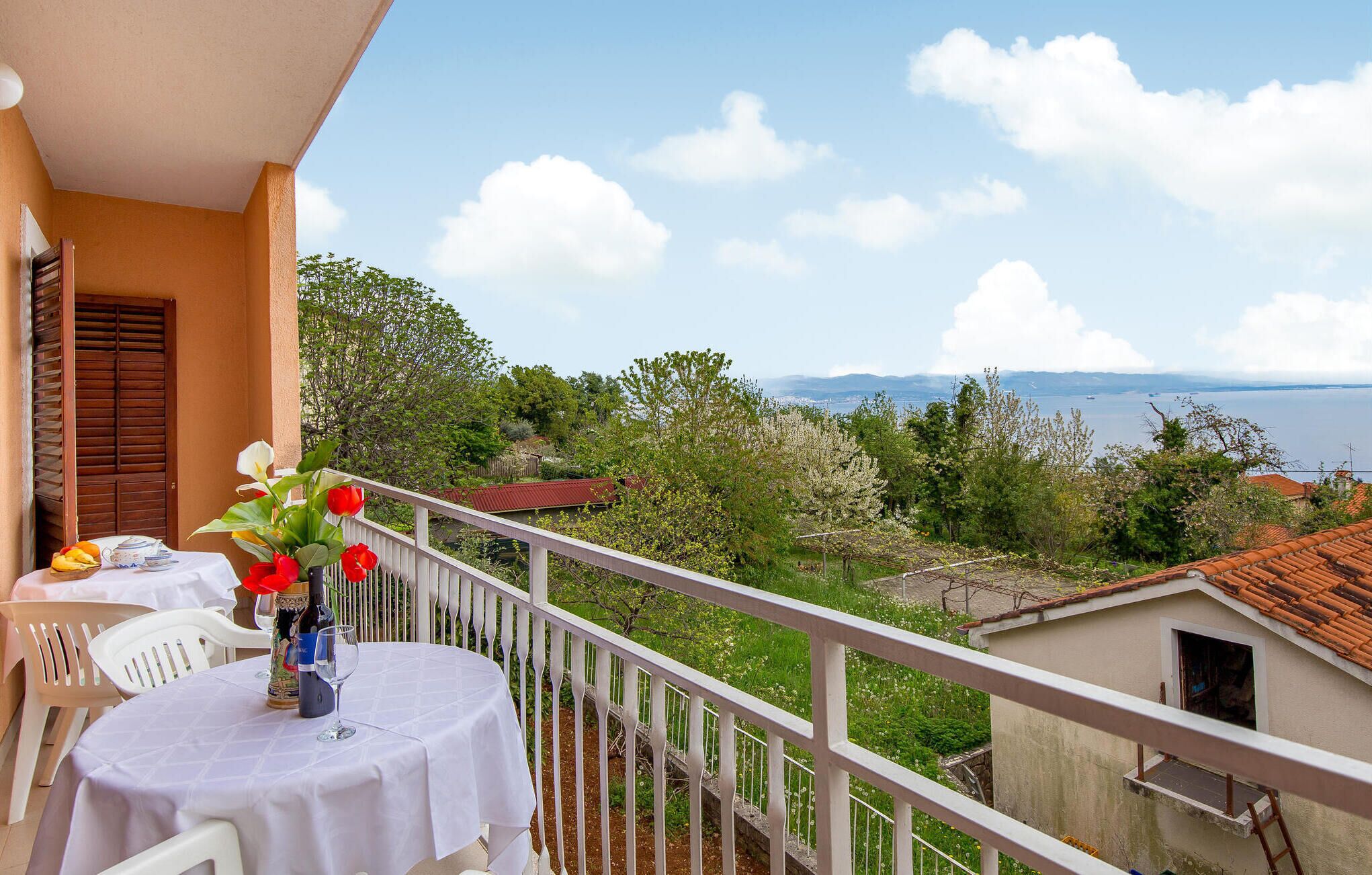 Balcón con una mesa preparada para dos, con vista a un paisaje que incluye agua y follaje.