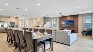 Una cocina moderna con comedor, una sala de estar con sofá y televisor, y una escalera.