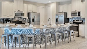 Una cocina moderna con una isla central, electrodomésticos de acero inoxidable y un salpicadero de azulejos azules.