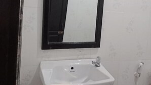 A bathroom with a white sink, a black-framed mirror, and a white tiled wall. - Chitlatda Guesthouse (Luang Prabang)