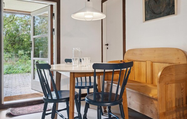 En matplats med ett bord, stolar, en bänk och en hängande lampa.