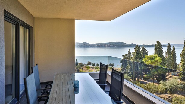 Ein Balkon mit Tisch und Stühlen mit Blick auf einen See und Hügel.