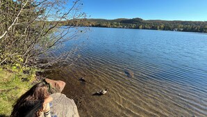A clear view of a lake with a rocky shoreline and trees in the background.