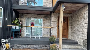 A modern house with a stone facade, a wooden deck, outdoor seating, and a mailbox.