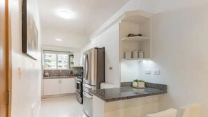 A modern kitchen with white cabinetry, a granite countertop, and stainless steel appliances.
