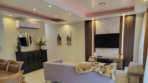 A modern living room with a sofa, a dining table, and a TV.