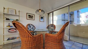 Een eetgedeelte met rieten stoelen, een glazen tafel en een hanglamp.