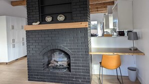 A modern kitchen with a black brick fireplace, wooden beams, and white cabinetry. - Beautiful beachfront Villa on 80 acres of farmland! (Sooke)