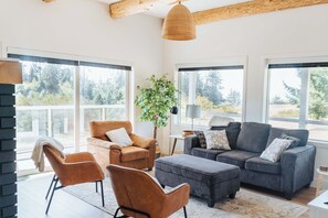 Amplia sala de estar con un ventanal, chimenea y una zona de estar acogedora con una planta.
