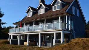 A two-story house with a balcony, a garage, and a chimney. - Beautiful beachfront Villa on 80 acres of farmland! (Sooke)